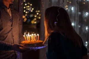 אישה מביעה משאלה ומכבה נרות על עוגת יומולדת
