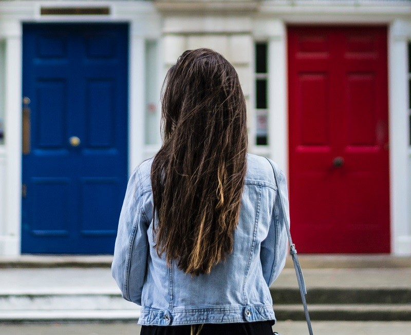 אישה עומדת בפני בחירה: דלת אדומה או כחולה