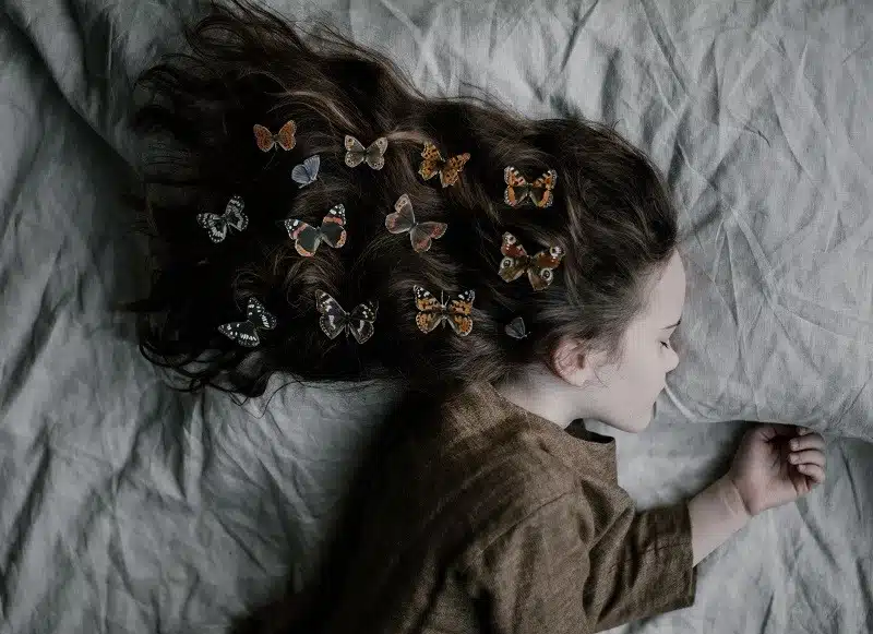 ללכת לישון מוקדם ובשמחה: בחורה צעירה ישנה עם פרפרים בשיער