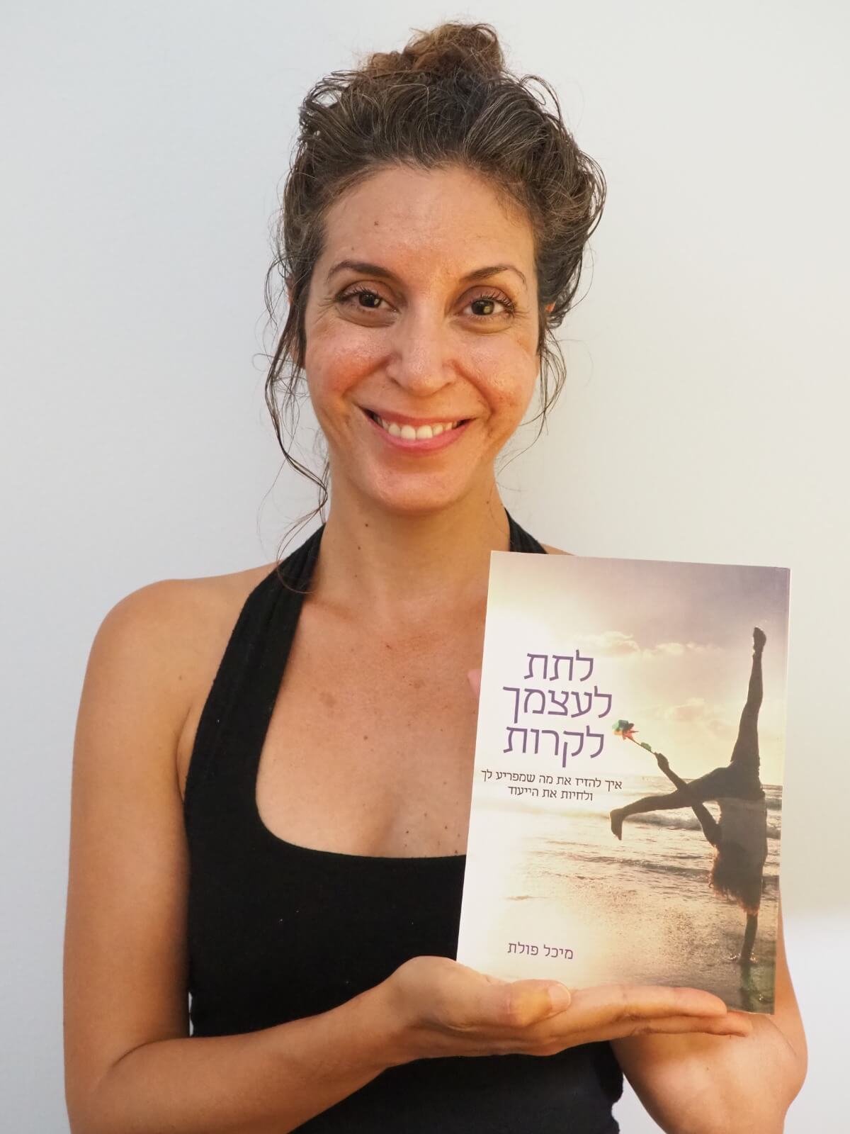 מיכל פולת מחזיקה ביד את הספר והמסר: לתת לעצמך לקרות