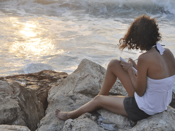 Michal polat journaling in front of the beach