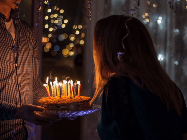 אישה מביעה משאלה ומכבה נרות על עוגת יומולדת