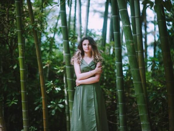 woman standing and hugging herself between bamboo trees